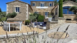 A stone building with a patio area featuring outdoor seating and a pergola. - Rural bastide and outhouse with private pool (Apt)
