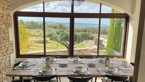 A dining area with a large window offering a view of a landscaped garden and distant mountains.