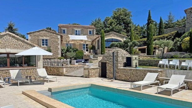 A pool area with lounge chairs and a stone building in the background.