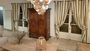 A room with a wooden cabinet, a table with a vase and a candle, and a unique chandelier with shell-like decorations.