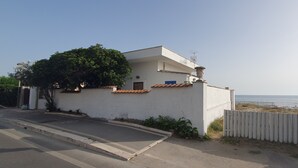 Un edificio blanco con techo de tejas y un pequeño balcón, con vista al mar.