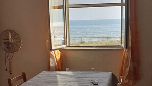 Una habitación con una mesa de comedor, sillas, un ventilador y una ventana con vistas al mar.