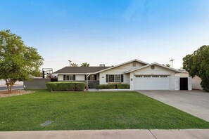 A single-story house with a garage, a well-maintained lawn, and a clear sky. - Tempe Delight-Heated Pool, Sport Court & King Beds (Tempe)