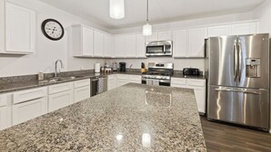 A modern kitchen with white cabinets, granite countertops, stainless steel appliances, and pendant lighting. - Tempe Delight-Heated Pool, Sport Court & King Beds (Tempe)