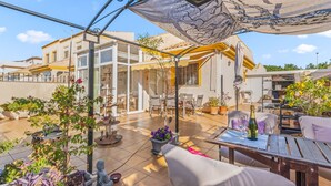 Un patio techado al aire libre con una mesa de comedor, sillas y plantas en macetas.