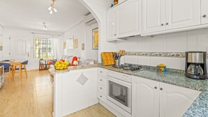 Una cocina con armarios blancos, encimera de granito, estufa y cafetera.