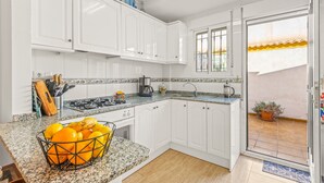 Una cocina con armarios blancos, encimera de granito y ventana con vistas a un edificio.