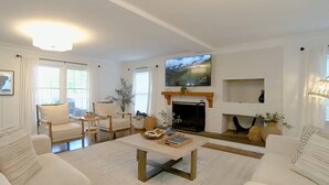 A living room with a fireplace, a television mounted above it, and a coffee table with books and decorative items. - Lake Escape - Beautiful Lake Views! - Hot Tub - Game Room - Kayaks - Dock - Firepit - Pet Friendly (Sherrills Ford)