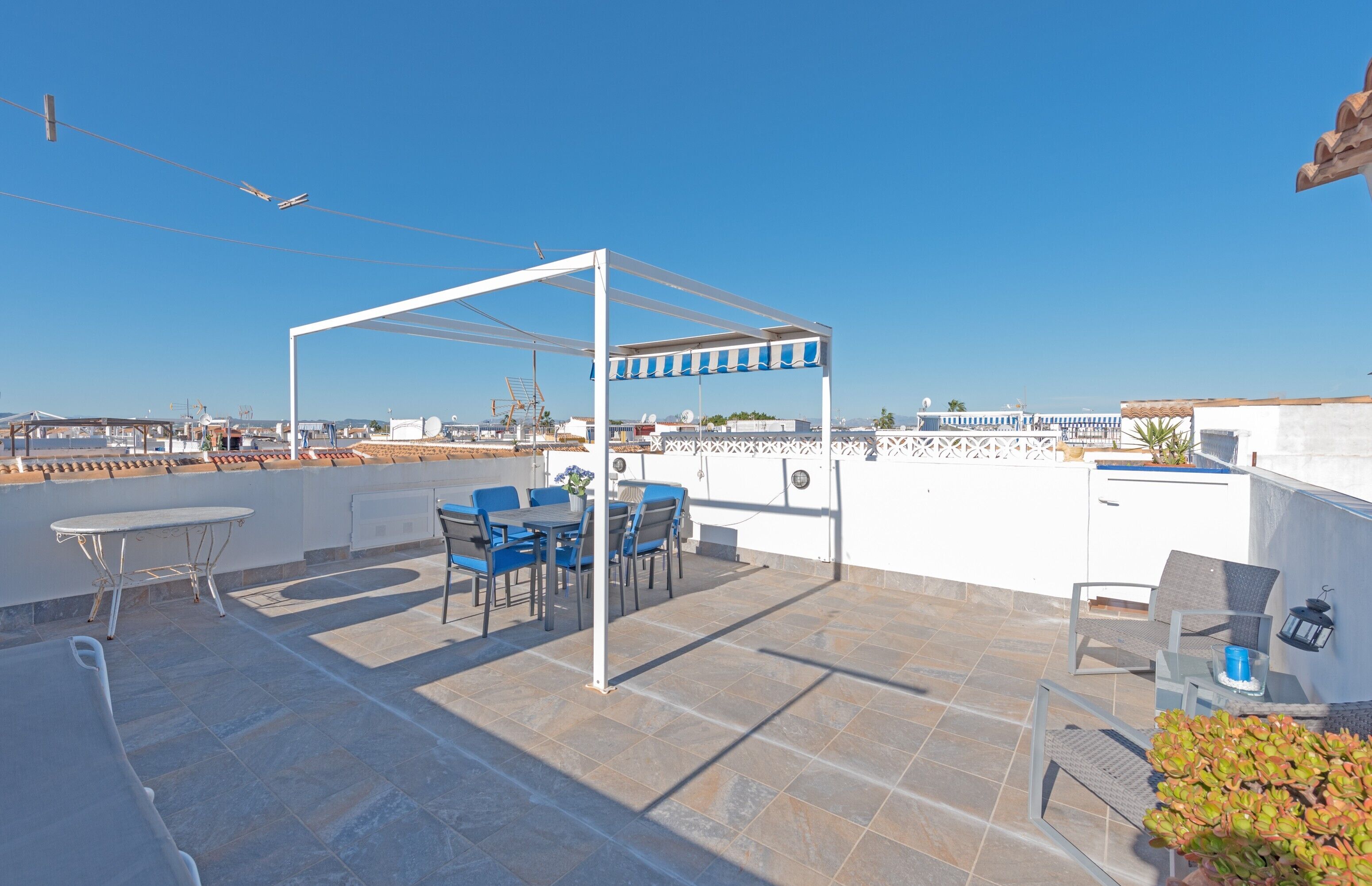 Terraza en la azotea con pérgola, mobiliario exterior y vistas de la ciudad.
