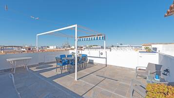 Terraza en la azotea con pérgola, mobiliario exterior y vistas de la ciudad.