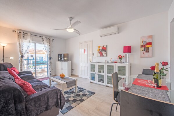 Un salon moderne comprenant un canapé, une table à manger, un meuble vitré et un ventilateur de plafond.