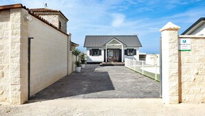 A building with a stone facade, a metal roof, and a paved entrance area with potted plants. - Chalet "Casa Manoli" with Pool, Terrace, Air Conditioning and Wi-Fi (Barrio Nuevo)