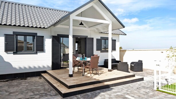A white building with a covered patio, a table with chairs, and a view of the sky. - Chalet "Casa Manoli" with Pool, Terrace, Air Conditioning and Wi-Fi (Barrio Nuevo)