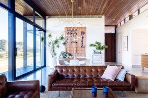 Relax in this stylish living room with a large sofa and armchairs, offering a view of the outdoors.