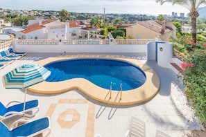 A swimming pool with a curved edge, lounge chairs, and a decorative umbrella. - Villa with Private Pool, Sea Views, Terrace, Balcony, A/C & Wi-Fi (Calpe)