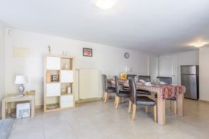 A dining area with a table, chairs, a clock, a refrigerator, and a radiator.