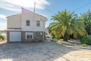 A two-story building with a stone-paved courtyard, a palm tree, and a white door. - Villa with Private Pool, Sea Views, Terrace, Balcony, A/C & Wi-Fi (Calpe)