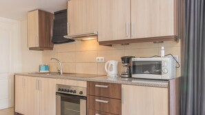 Una cocina moderna con armarios de madera, horno empotrado, microondas y cafetera.