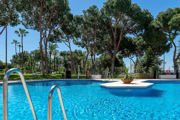 A swimming pool with clear blue water, surrounded by trees and a lifebuoy.
