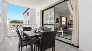 A balcony with a dining table, chairs, and a view of a building. - Apartment 'Puerto Banus2 Beachfront and Pools' with Shared Pool, Wi-Fi and Air Conditioning (Puerto Banús)