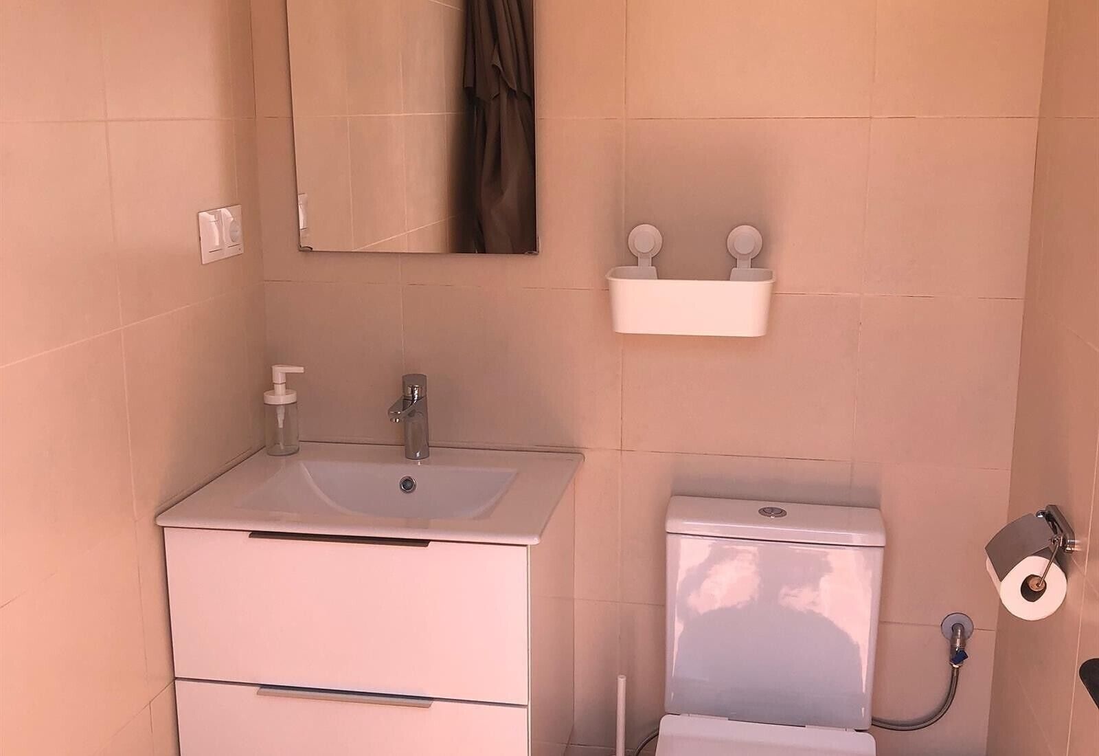 Une salle de bain équipée d’un lavabo, d’un miroir, de toilettes et d’un porte-serviettes.