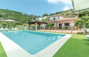 Una piscina con sillas de descanso, un porche cubierto y vistas a una colina.