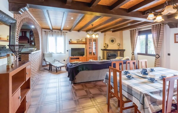 Una habitación acogedora con una cama, una mesa de comedor para dos personas, un televisor y una chimenea.