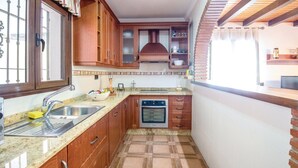 Een kleine keuken met een ingebouwde oven, een spoelbak en houten kastjes.