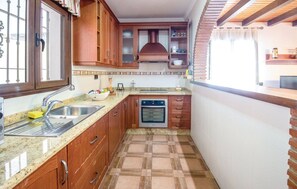 Une cuisine compacte dotée d’un four encastré, d’un évier et de meubles de rangement en bois.