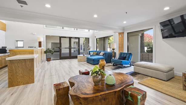 A spacious living area with a wooden coffee table, blue sofas, and a TV mounted on the wall. - Hotel Huntington (Duarte)