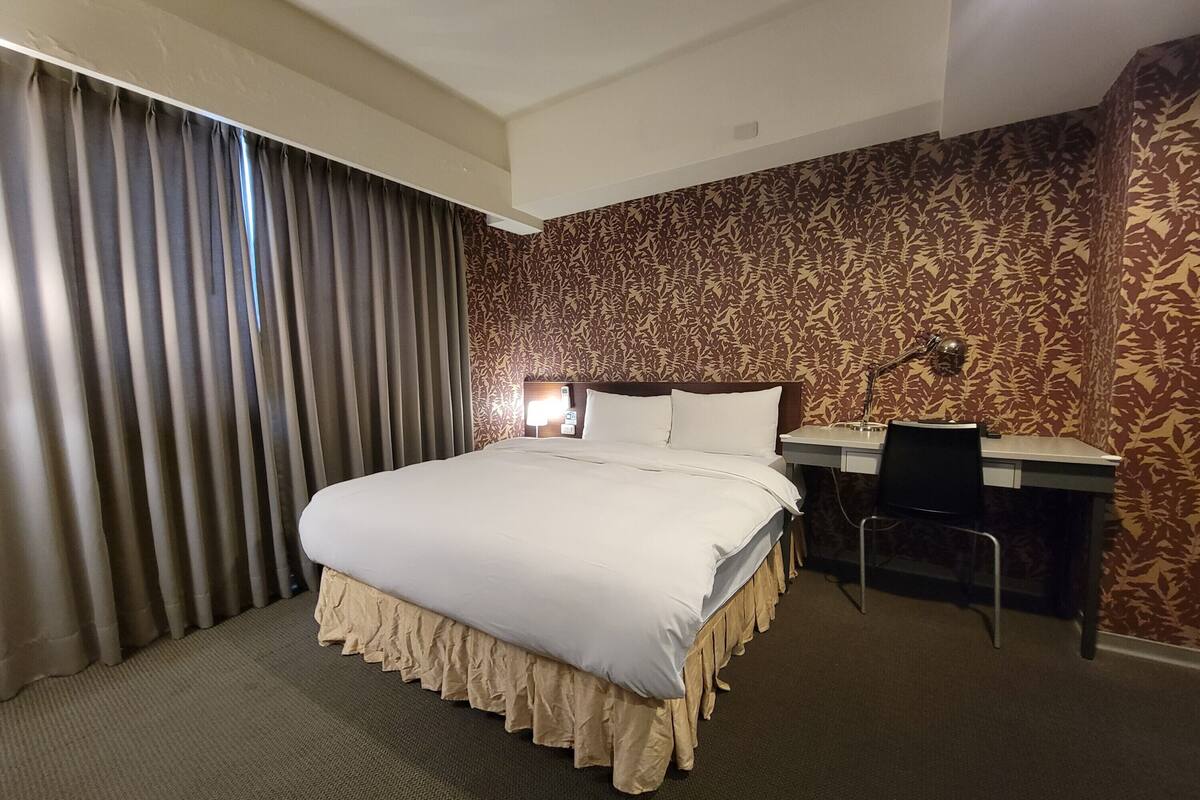 Een hotelkamer met een groot bed, een bureau en een stoel.