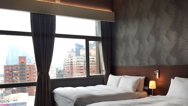 Habitación de hotel con dos camas, vistas a la ciudad y una pared con diseño.