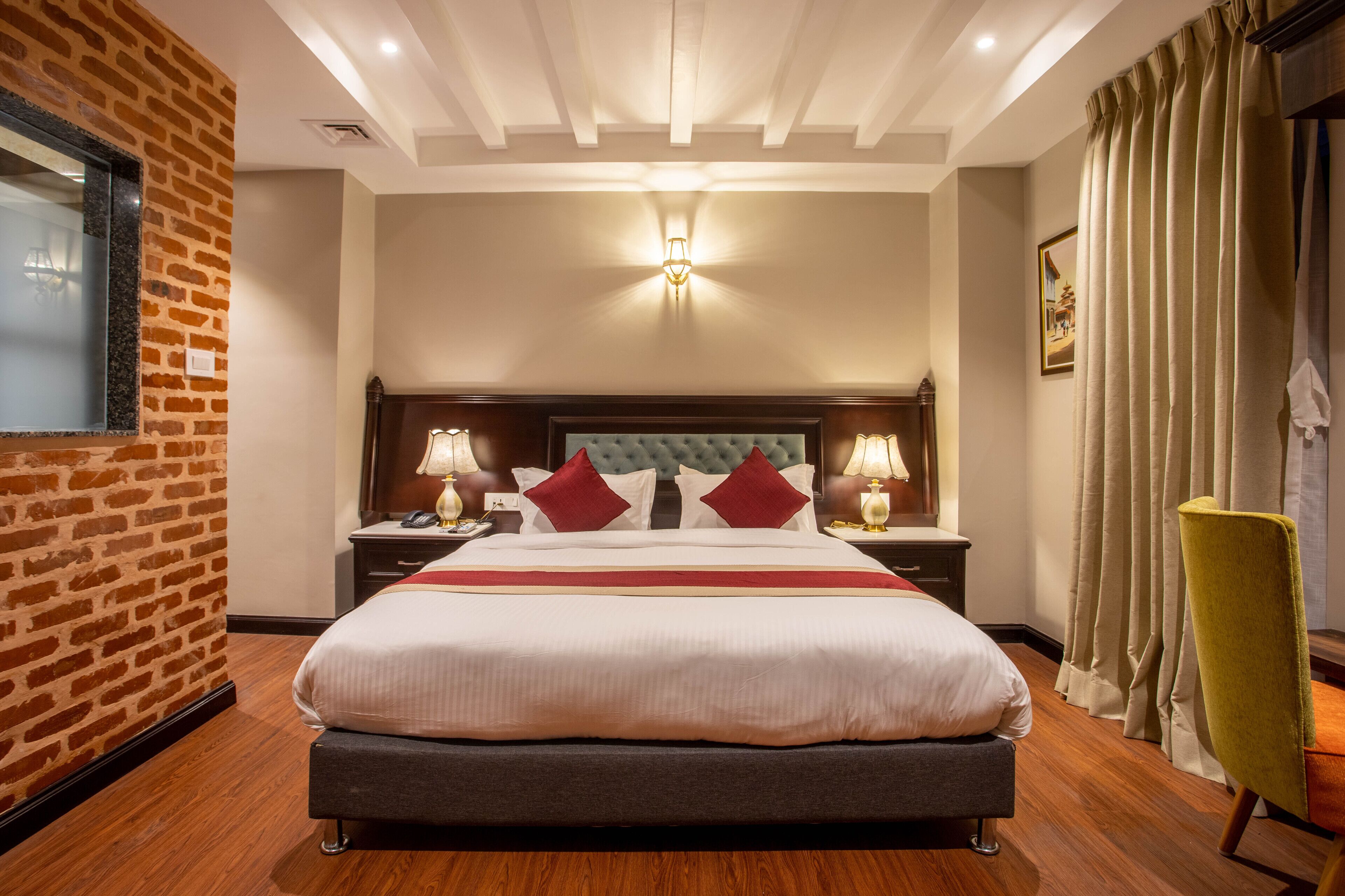 Une chambre d’hôtel avec un grand lit, deux tables de chevet avec des lampes, un mur décoratif en briques et un plancher en bois.