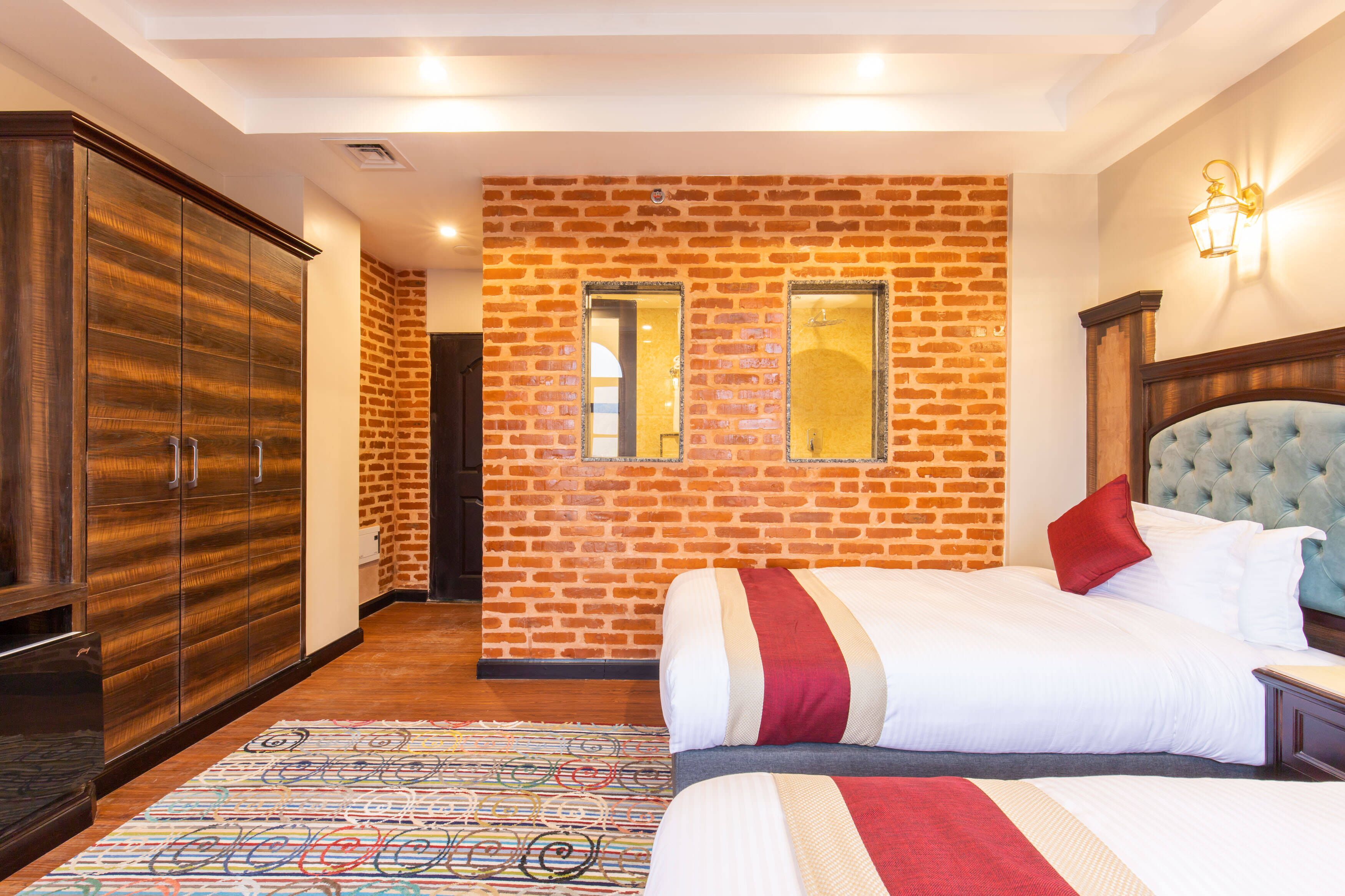 Habitación de hotel con pared de ladrillo, cama grande con muchas almohadas, armario y una mesita.