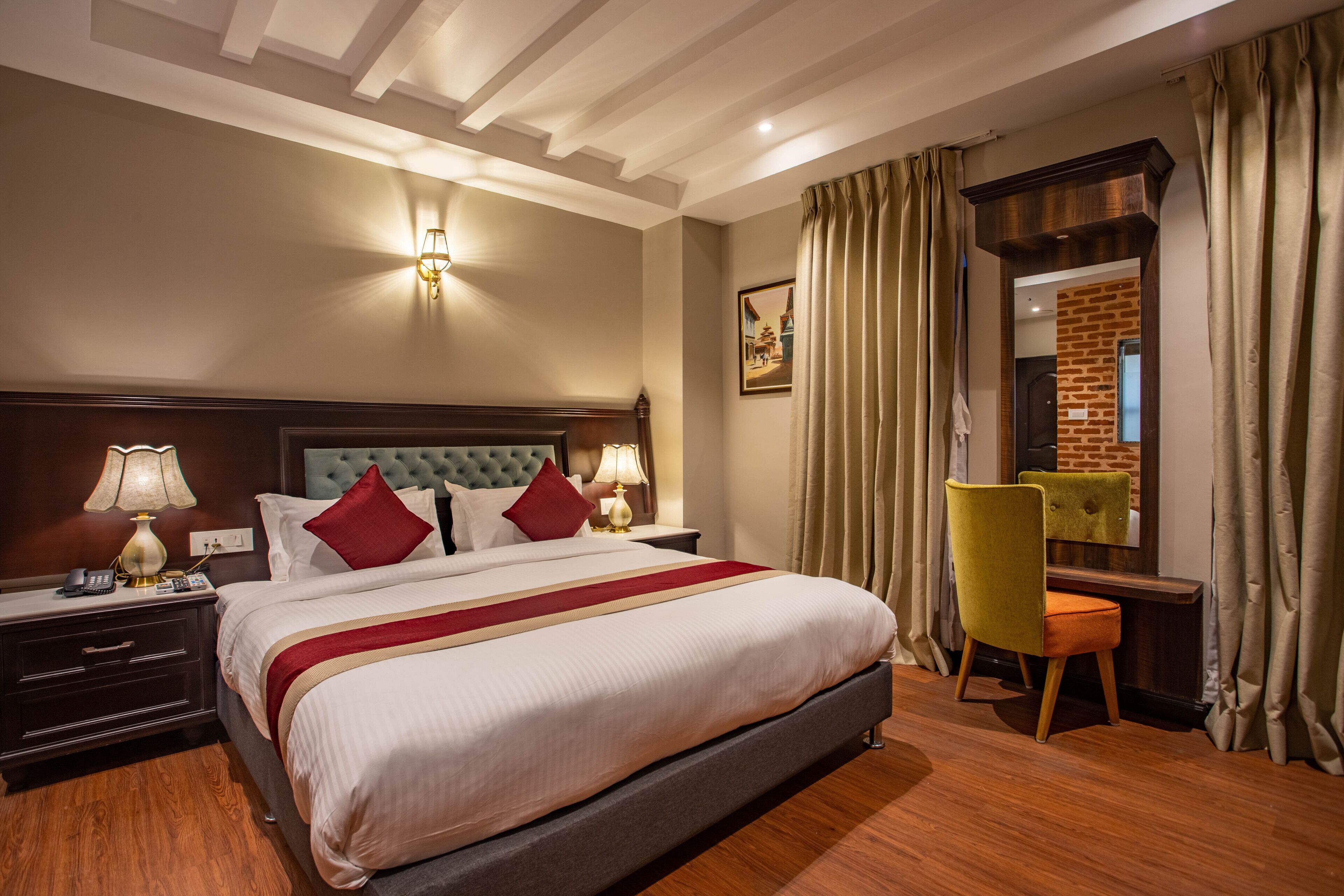 Une chambre d’hôtel avec un grand lit, un bureau et une chaise. Il y a une lampe sur le bureau et un tableau au mur.