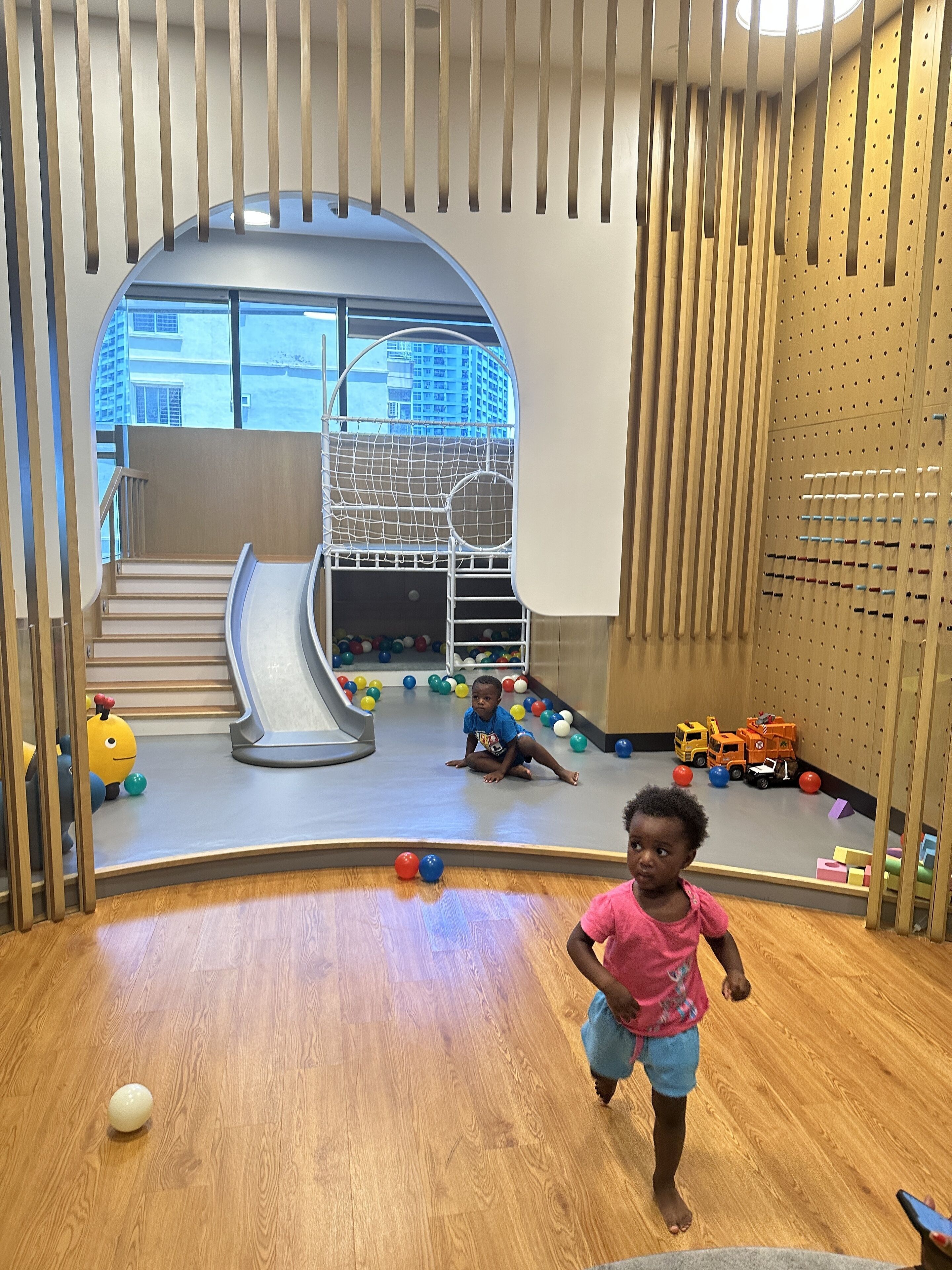 A play area with a slide, climbing net, and various toys.