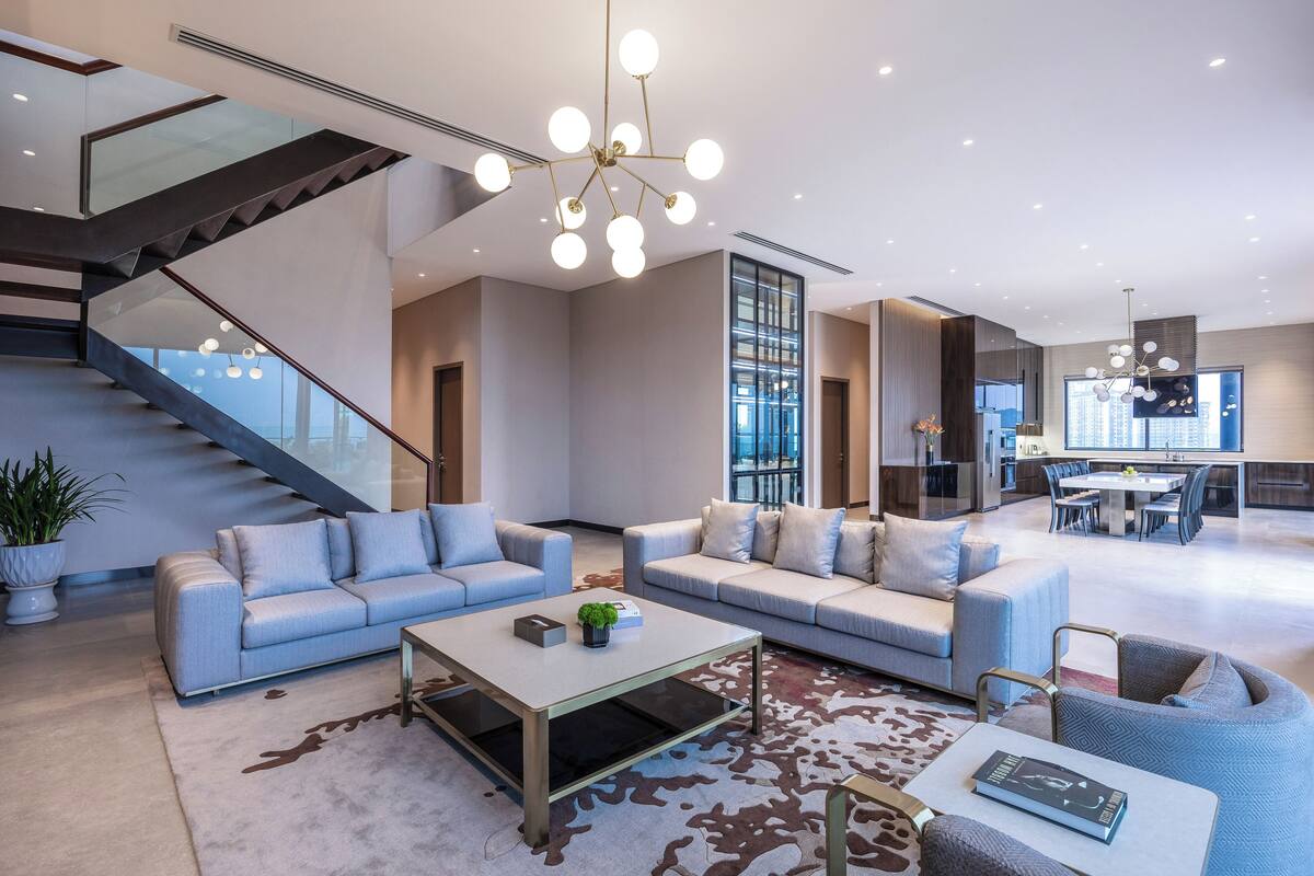 A modern living room with a staircase, a dining area, and a kitchen.