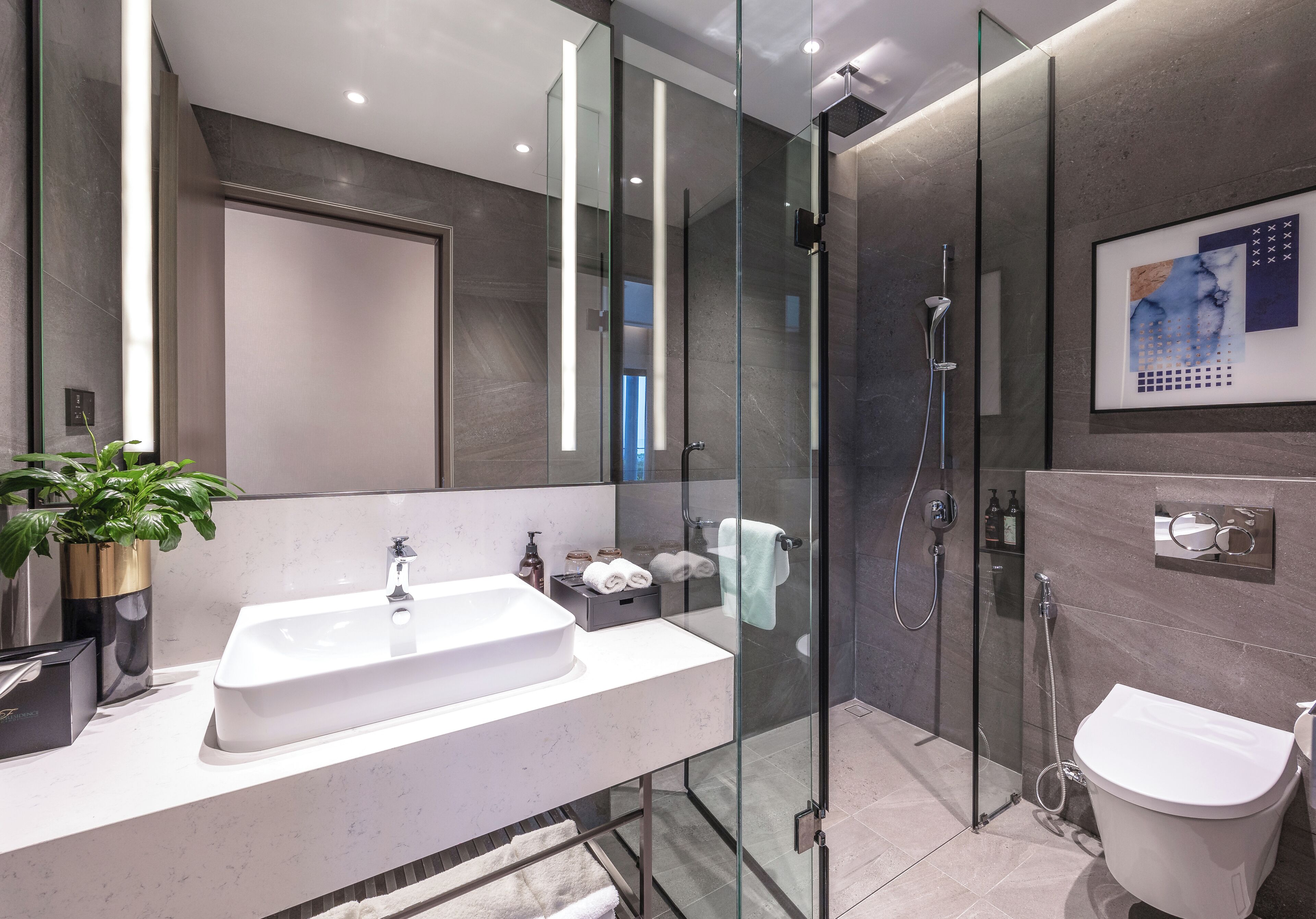 A modern bathroom with a glass-enclosed shower, a white sink, and a toilet.