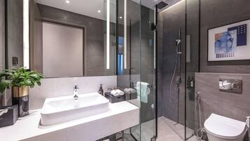 A modern bathroom with a glass-enclosed shower, a white sink, and a toilet.