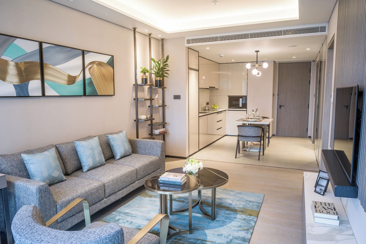 A modern living room with a sofa, coffee table, and a dining area with chairs.