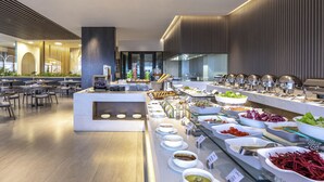 Zona de bufé con diversas estaciones de comida, disposición de asientos y diseño de interiores moderno.