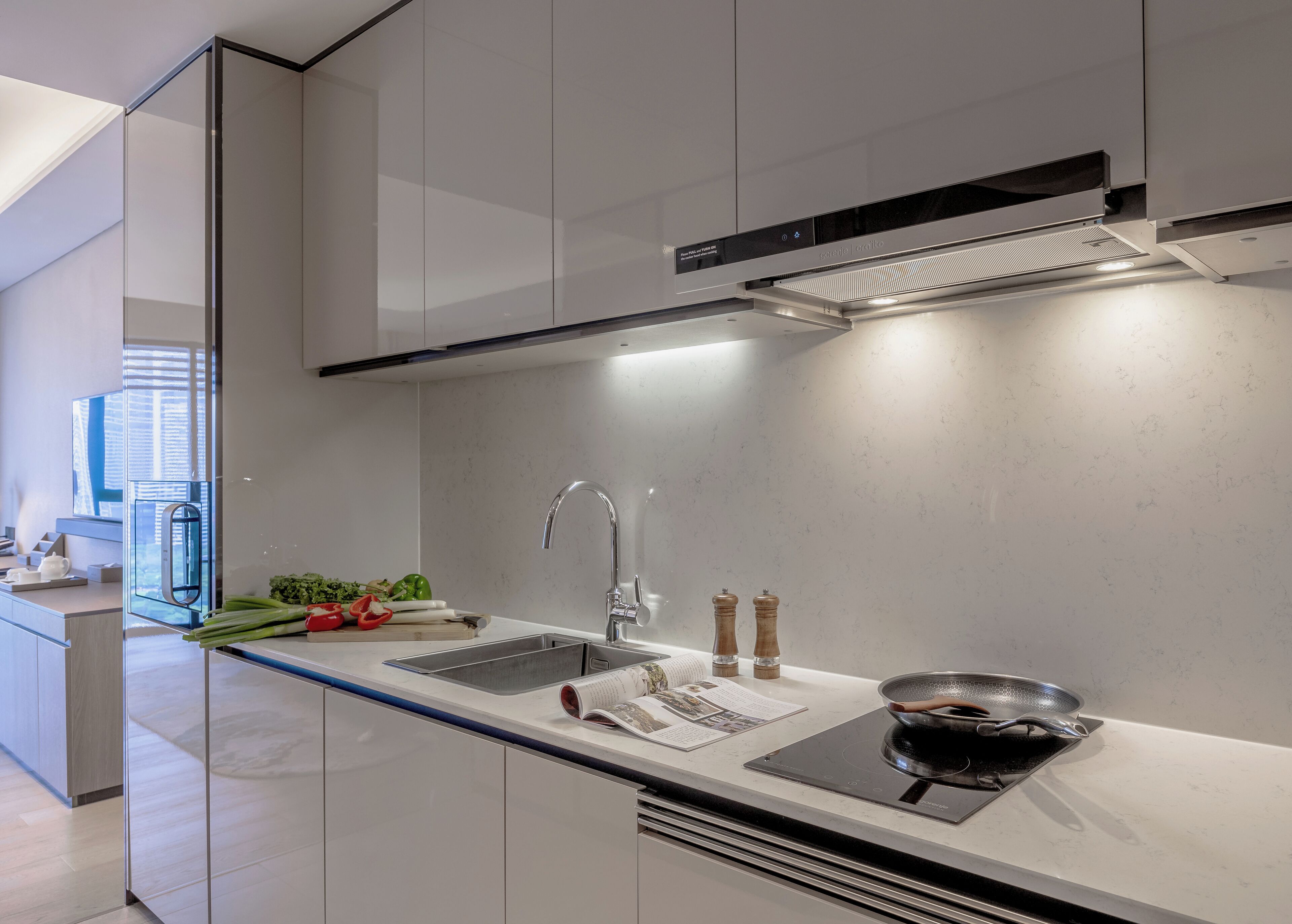 A modern kitchen with a sleek design, featuring a stainless steel sink, a built-in stove, and a large window providing natural light.