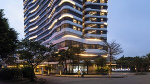 Un edificio moderno de gran altura con fachada curva, varios balcones y ventanas iluminadas.