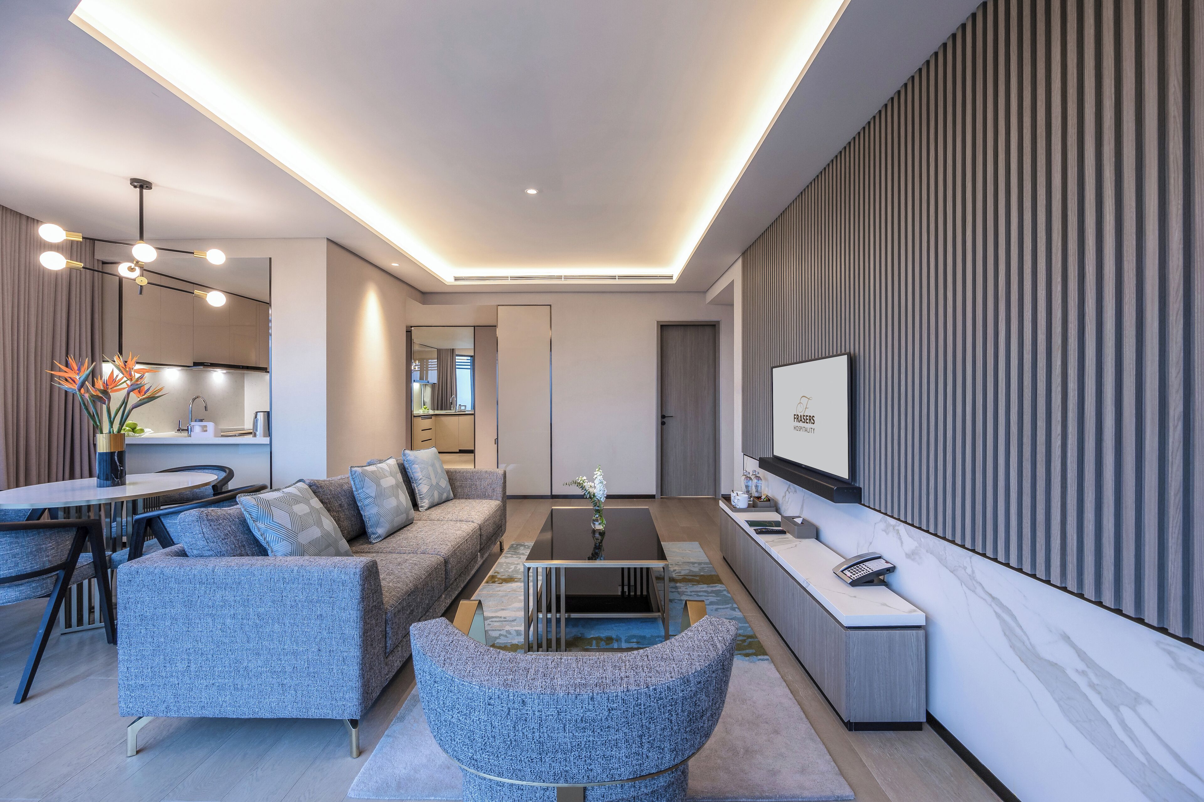A modern living room with a sofa, coffee table, and a TV on the wall.