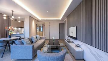 A modern living room with a sofa, coffee table, and a TV on the wall.
