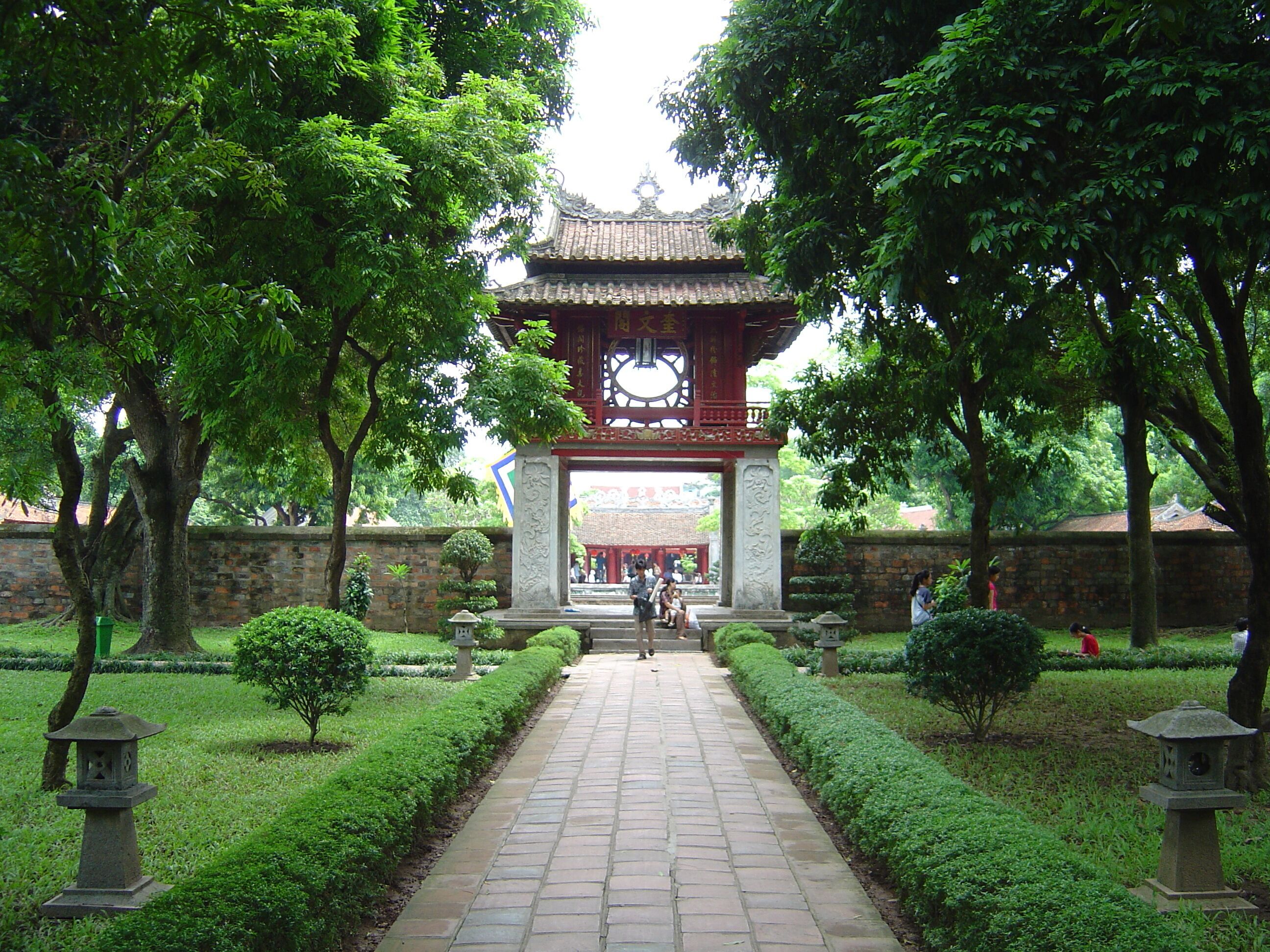 A traditional gate with intricate carvings, a stone pathway, and well-maintained greenery.