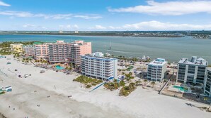 Un hôtel situé en bord de mer, composé de plusieurs bâtiments, avec une plage de sable et une vue sur l’océan.