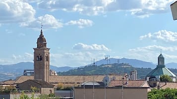 Vue d’une ville avec un clocher d’église imposant et une chaîne de montagnes en arrière-plan.