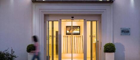 The entrance of Hotel Card International with a glass door and a sign above.