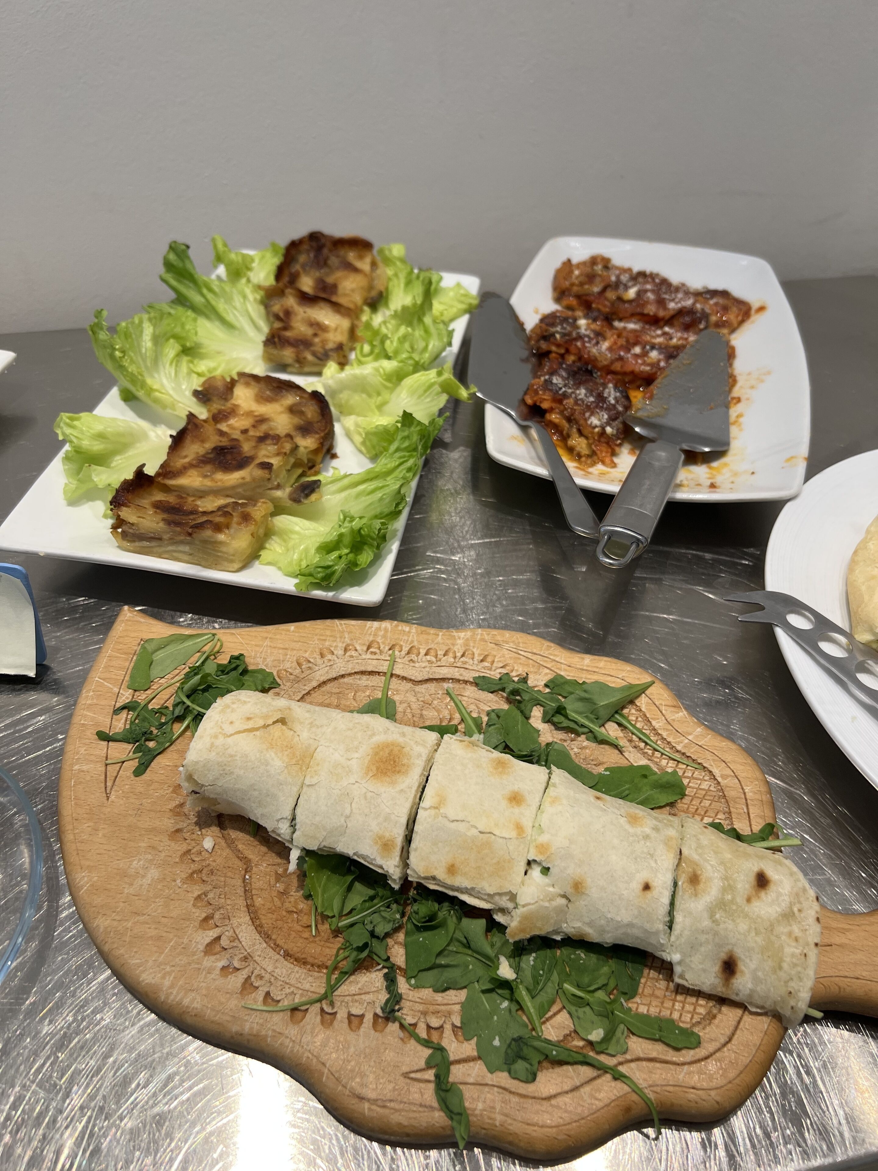 Un tavolo con diversi piatti, tra cui carne alla griglia, un burrito e un piatto con coltello e spatola.